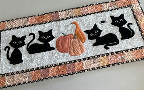 "36\" x 14\" autumn themed table runner or wall hanging pattern for quilting. A simple pieced border surrounds four big eyed cats. Those watching eyes catch everything. The feline friends guard their three pumpkins while the itsy-bitsy spider keeps them company. The table runner is perfect for the entire pumpkin season and a great addition to Halloween decor.  The pattern is clearly written with numerous photos and charts to explain every step of the sewing. Full size templates as well as layout Autumn Cats, Wall Hanging Pattern, Mug Rug Patterns, Halloween Table Runners, Christmas Quilt Patterns, Hanging Quilts, Quilted Table Runners Patterns, Baby Quilt Pattern, Halloween Quilts