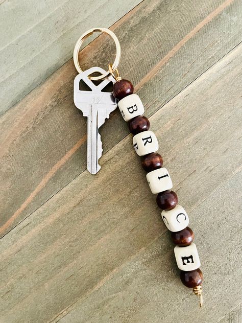 This minimal bead key chain is very useful.  It would make a great gift for  someone or you may want one for yourself.  Your keychain will be made with light and dark colored wood beads and may be personalized.  Simply place the name that you want in the personalization area and I will create your keychain.  I have gold tone key rings and silver tone rings as well.  The alphabet letter beads are alternated with dark wooden beads to create this minimalist look.  The length of your keychain will depend on the number of letters that are in your name.  The one pictured is about 5 inches long and has 5 letters. Bead Keychain Men, Masculine Keychain Diy, Beaded Keychain For Men, Letter Beads Keychain, Keychain Ideas For Men, Diy Keychain For Him, Key Chains For Men, Personalized Gifts Christmas, Men Keychain