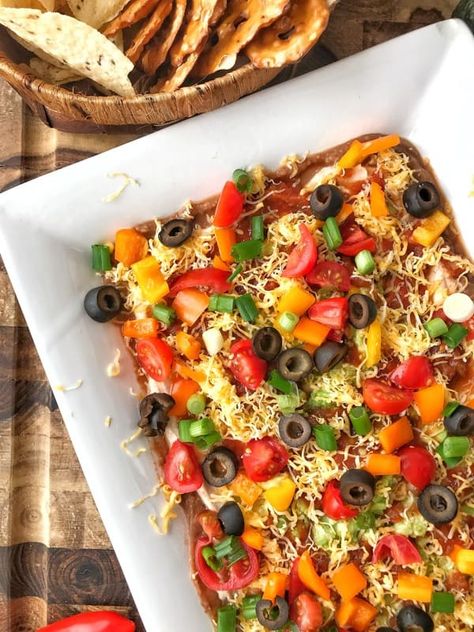 Layered Taco Dip Recipe: This healthy layered taco dip is easy to make. Using refried beans, greek yogurt, spices, salsa, and loads of veggies, its the perfect appetizer for game day or parties. Enjoy with tortilla chips, pretzel chips or even veggie sticks. Taco Dip With Refried Beans, Pretzel Chips, Layered Taco, Veggie Sticks, Taco Dip Recipe, Layered Taco Dip, Party Dip Recipes, Taco Dip, Bowl Recipes