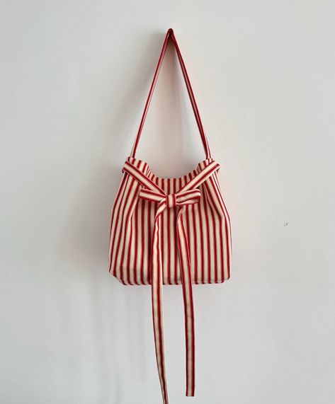 Red and cream  stripe  padded shoulder bag with tie up closure. Made from organic vintage stripe  Linen. This bag is attributed to its timeless, versatile design. Would look cute with any outfit. It's sustainable and chic to retro aesthetics. We use our own patterns and designs. if you would like a different size please message us we can create a custom listing. Please allow 3-4 days to get your order made. Size Height 12 width 11.5 Debth 2. 5 inches  WORLDWIDE SHIPPING  If you have an questions Cream Bag, Cream Bags, Bow Bag, Striped Bags, Red Bag, Quilted Bag, Red Stripe, Cute Bags, Striped Linen