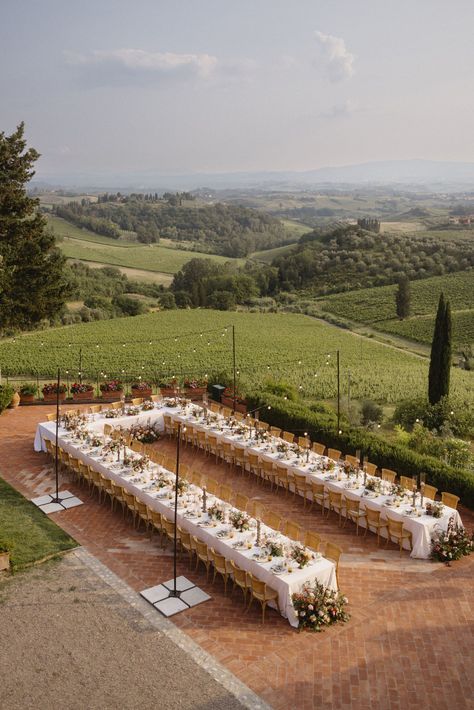 Long dining tables arrange for an outdoor wedding reception in Tuscany, Italy. Rolling hills captured in the backdrop. Outdoor Wedding Long Tables, One Big Wedding Table, Tuscany Wedding Table Decor, Garden Wedding Italy, Italian Vibes Wedding, One Long Table Wedding Reception, Wedding Reception Long Tables, Wedding Table Long, Long Table Wedding Reception