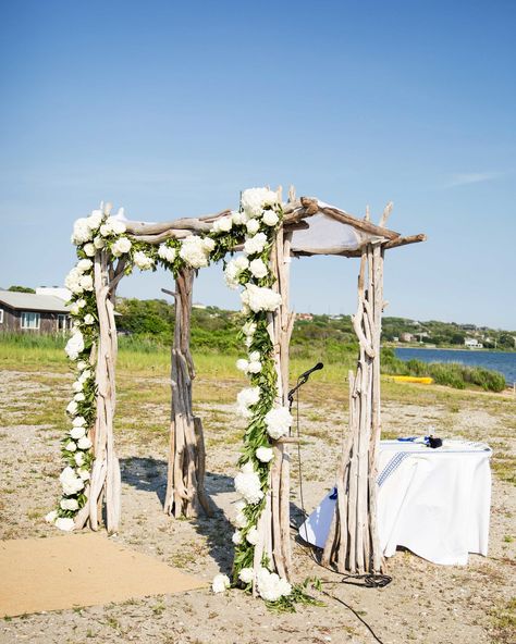 The chuppah was erected on Montauk's East Lake beach, in between the couple's summer house and the Montauk Bungalows (where many of the guests stayed). The driftwood structure was adorned with white blooms and trailing greenery. "A 1000 Times" by Hamilton Leithauser and Rostam played during the processional, before the Rolling Stones' "She's Like a Rainbow" played as Kelly entered with her mother. The Jewish ceremony included the traditional reading of the seven blessings. Driftwood Chuppah, Hamilton Leithauser, Wedding Reception Decor Ideas, Montauk Beach, Reception Decor Ideas, Beach Wedding Decorations Reception, Beach Wedding Reception, Beach Wedding Flowers, Boho Beach Wedding