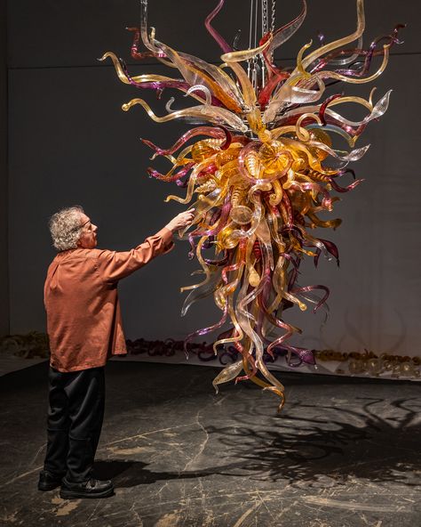 “To this day, I have never gotten over the excitement of molten glass…the process is so wonderfully simple, yet so mystifying.”—#Chihuly   Chihuly reviewing “Iris Gold and Garnet Chandelier” at Chihuly Studio in Seattle (2022), now on view at Biltmore Estate.  © Chihuly Studio  ____________________ #DaleChihuly #ChihulyGlass #Glass #GlassArt #Glassblowing #Art #FineArt #Chandelier #ChihulyChandelier #Iris #Garnet #Studio #Gold #Biltmore #BehindTheScenes Glass Blowing Art, Chihuly Chandelier, Hide Video, Brooklyn Botanical Garden, Transparent Art, Seattle Art, Dale Chihuly, Biltmore Estate, Blown Glass Art