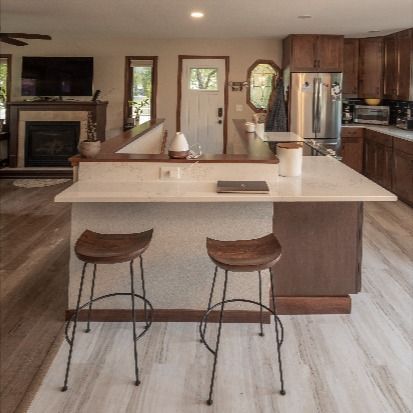 When your staircase is in the entryway, butting up into your kitchen, creating open concept is a challenge. For this remodel, we opened up the staircase and wrapped the kitchen counter around it to create a functional island while allowing for an open concept flow throughout the main level. Check out the before photo to see how boxed in this space felt before we got our hands on it! Kitchen Island With Stairs To Basement, Kitchen With Stairs In Middle, Kitchen Island Meets Staircase, Stairs In Kitchen Layout Open Floor, Stairs Under Kitchen Island, Kitchen Next To Stairs, Open Stairs In Kitchen, Open Concept With Stairs In Middle, Open Basement Stairs In Kitchen