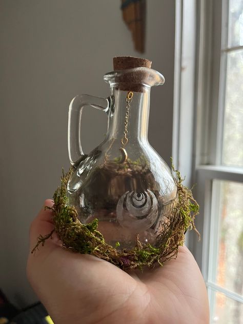 Fairy Bottles for any witchy, gothic, fairy-loving person! These bottles are made from moss, bottles, beads, chains, and glass armour. A great addition to any home.  Video on how it is made:  https://youtu.be/9KPvtRpJbbQ?feature=shared https://youtu.be/hZkWfI7NwVE?feature=shared Fairy Dust Bottles, Green Witch House Decor, Cute Glass Bottles, Fairy Forest Decor, Fairy Core Home Decor, Glass Bottles Aesthetic, Fairy Bathroom Ideas, Diy Witchy Crafts, Elven Decor