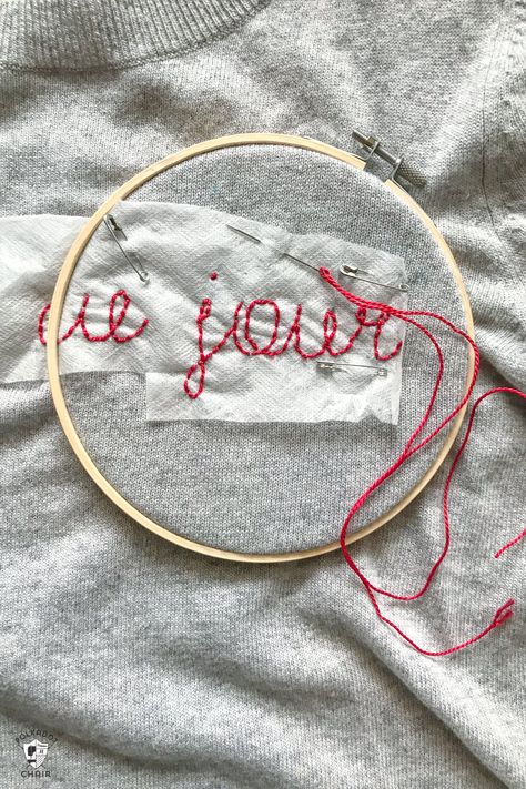 Learn how to make a DIY Embroidered sweater with a fun french quote on it. Includes free embroidery pattern for the quote. A clever way to refashion an old sweater. #DIYEmbroidery #DIYFashion #embroideredsweater #tutorial Embroidery In Sweater, Diy Name Embroidery Sweatshirt, Embroidering Sweatshirts Diy, Chain Stitch Name Sweater Diy, Embroidering A Sweater, How To Embroider A Sweater, Hand Embroidery On Sweater, Embroidery Names On Clothes, Yarn Embroidery On Sweater Diy