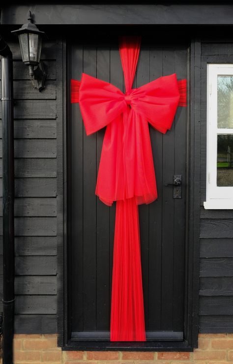 Christmas Ribbon On Door, Red Christmas Door Decoration, Door Wrapping Christmas, Front Door Wrapped Like Present, Front Door Tulle Bow, Christmas Bow Decor Ideas, Gift Wrapped Door, Wrap Door Like Present, Front Door Bows Christmas