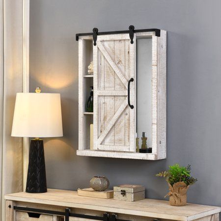 Storage solutions should not only be functional, but fashionable too. We hear you. Reminiscent of a sliding barn door in an old farmhouse, the FirsTime & Co. Winona Farmhouse Barn Door Cabinet Mirror offers the perfect rustic touch to any room. The fully functional door slides back and forth on rollers to reveal hidden storage space. Within the cabinet, choose to display either 3 useful shelves for treasured curios on one side or an elegant mirror on the other. Craed of wood, the cabinet has Farmhouse Barn Door, Barn Door Cabinet, Barn Bathroom, Bathroom Cupboard, Cabinet Mirror, White Barn Door, Wall Mounted Bathroom Cabinets, Elegant Mirrors, White Shelves