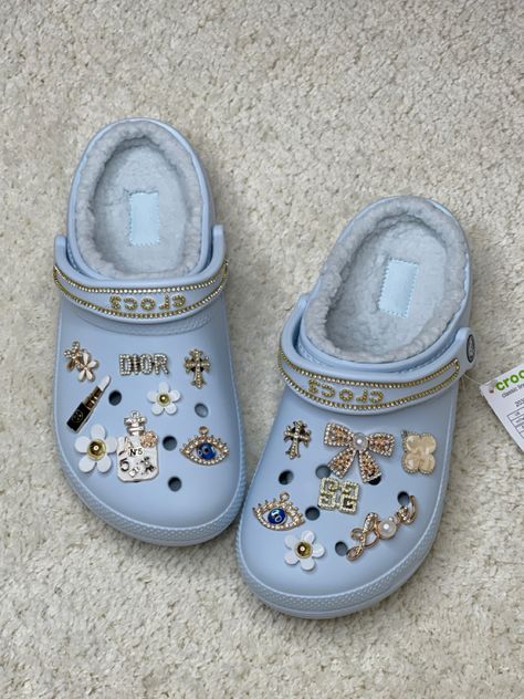 Cream coloured carpet with light blue crocs with gold charms and chains White Crocs Jibbitz Aesthetic, White Crocs With Gold Charms, Black Crocs With Gold Jibbitz, Light Blue Crocs With Charms, White Croc Jibbitz Ideas, Light Blue Crocs Outfit, Blue Crocs With Charms, Mineral Blue Crocs, Blue Crocs Aesthetic