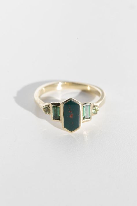 Art deco inspired ring with bloodstone and green tourmaline.

Bloodstone is inlaid into the elongated hexagon, measuring 9.5mm x 5mm. Accent tourmalines are approximately .30 total carat worth. Millimeter measurement from end to end is 15mm. Horizontal Gemstone Ring, Unique Black Rings, Art Deco Ring Emerald, Artist Engagement Rings, Bloodstone Ring Engagement, Emerald Green Engagement Rings, Bloodstone Engagement Ring, 5 Stone Engagement Rings, Green Garnet Ring