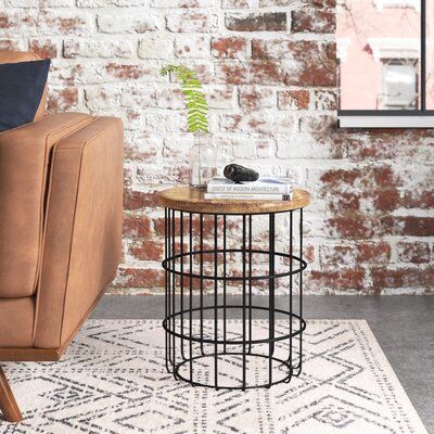 A handy touch whether sidled up to a sofa or beside a bed, end tables round out a room with a much-needed extra surface, while also complementing your ensemble's style. Take this one, for example: perfect for a breezy contemporary look, it's crafted from a black-finished, cage-like metal base with a solid mango wood surface for an on-trend mixed material look. Striking a cylindrical silhouette, this 17.8'' H x 15.75'' W x 15.75'' D helps break up the silhouettes of boxy furniture, while also del Wood And Black Metal End Tables, Leather Wingback Chair, Drum Coffee Table, Industrial Livingroom, Industrial Living, Into The Wood, Small Table Lamp, Console And Sofa Tables, Table Wood