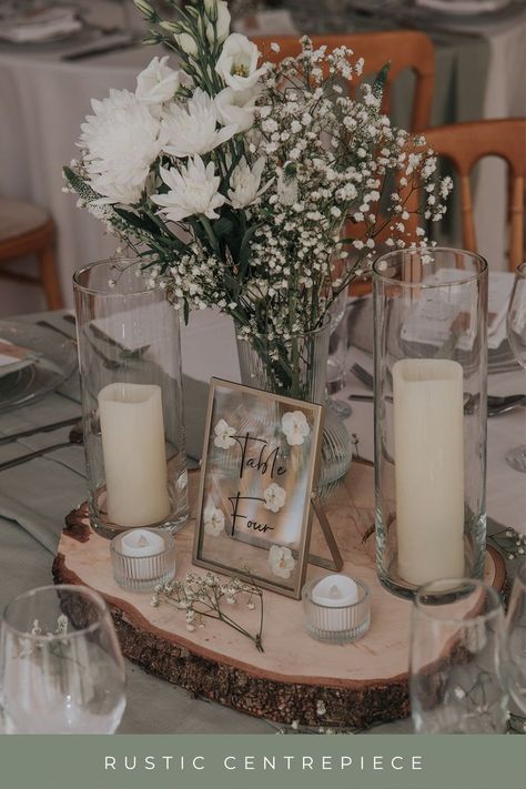 log slice, candles, green and white flowers, table number as a wedding centrepiece Wedding Decor Wood Slices, White Rustic Wedding Theme, Centerpieces Wedding With Table Numbers, Natural Wedding Centre Pieces, Rustic Elegant Centerpieces Wedding, Sage Green Wedding Centre Pieces, Wedding Wooden Centerpieces, Wedding Top Table Flowers Rustic, Green Table Centrepiece