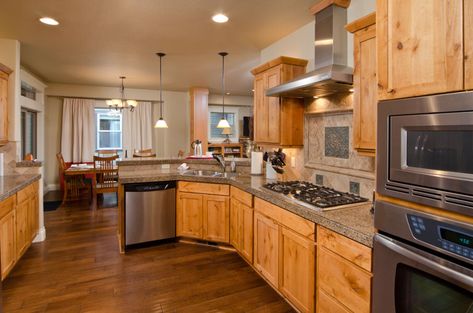 Kitchen with wood floor, oak cabinets, stove, hood, and recessed lights Honey Oak Cabinets With Brass Hardware, Vinyl Plank Flooring With Honey Oak Trim, Oak Cabinets With Dark Floors, Hardwood Floors With Oak Cabinets, Early American Stain On Oak Cabinets, Wood Floors With Honey Oak Cabinets, Honey Oak Cabinets With Dark Wood Floors, What Color Floor With Honey Oak Cabinets, Oak Cabinets With Wood Floors