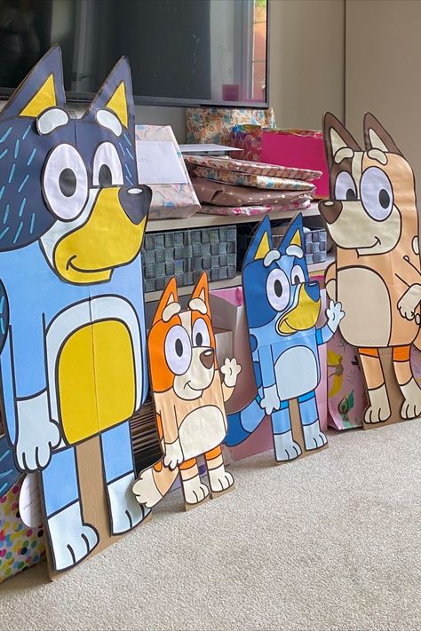 Four large Bluey character boards, setup in a lounge with presents behind. Trunk Or Treat Bluey Theme, Diy Bluey Centerpieces, Bluey Cardboard Cutout, Bluey Cut Outs, Diy Bluey Pinata, Diy Bluey Cutouts, Bluey Birthday Centerpieces Diy, Bluey Classroom Decoration, Diy Bluey Decorations