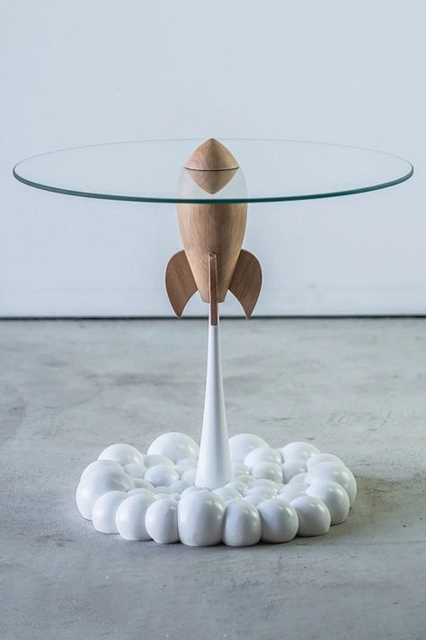 This cool new Rocket Table from the Mousarris Design Studio depicts a retro-futuristic sci-fi rocket ship blasting off into space with a glass tabletop riding on its nosecone and a puffy smoke trail exhaust doubling as its base. Space Themed Interior Design, Retro Space Decor, Space Ships Design, Scifi Furniture, Sci Fi Furniture, Futuristic Decoration, Futuristic Table, Spaceship Decor, Rocket Decorations