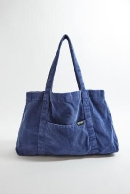 Oversized corduroy tote bag by BDG, a staple style for carrying all of your overnight essentials. Soft skinny cord fabrication Ft. two carry handles and a logo tab detail on one seam. UO exclusive. **Content + Care** \- 100% Cotton \- Spot clean | BDG Tab Corduroy Tote Bag - Blue at Urban Outfitters Bdg Corduroy Tote Bag, Overnight Essentials, Urban Outfiters, Corduroy Tote Bag, Tote Bags For School, School Tote, Blue Tote Bag, Oversized Tote Bag, Oversized Tote