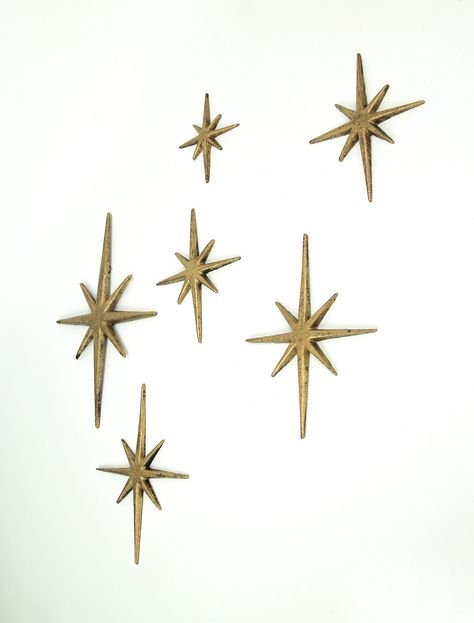 This sextet of 8 pointed compass stars adds a wonderful Mid-Century modern touch to your indoor or outdoor decor. Crafted of cast iron, the stars feature an antiqued enamel finish to give them a great aged look. Each set has one XL star measuring 8.75 inch long, 0.25 inch wide, 12 inch high; two large stars measuring 7 inch long, 0.25 inch wide, 8.75 inch high; two medium stars measuring 5.75 inch long, 0.25 inch wide, 6.75 inch high, and one small star measuring 4.25 inch long, 0.25 inch wide, Star Decorations, Wall Decor Set, Gold Walls, Dream House Decor, Room Themes, House Inspo, Metallic Gold, Wall Hangings, House Decor