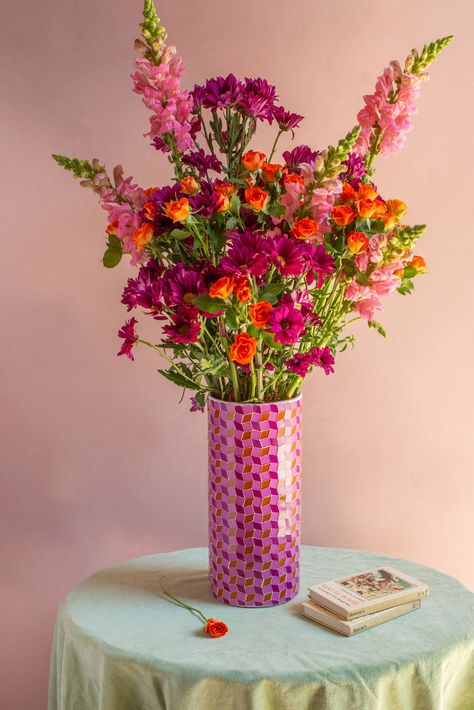 A striking cylindrical mosaic glass vase perfect for all your floral displays. Pink tones and orange glass pieces have been arranged in a intricate design creating a bold, contemporary look. This vase is a wonderful centrepiece; whether table, shelf or windowsill. Flower Stall, Orange Mosaic, Picnic Dates, Flower Bouquet Vase, Red Mosaic, Ian Snow, Pink And Orange Flowers, Mosaic Vase, Uni Room