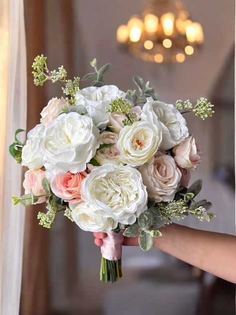 The blush pink bridesmaid bouquet is a stunning arrangement that perfectly complements any wedding theme with its soft, romantic hues. Featuring a delicate blend of blush pink, peach, and cream tones, this artificial bouquet combines the elegance of cream roses with the subtle beauty of peach wedding flowers. The carefully crafted design ensures that the bouquet looks as fresh and vibrant as real flowers, making it a lasting keepsake from your special day. Ideal for both bridesmaids and the brid Peach And White Wedding Bouquet, Peach And Sage Wedding Flowers, Blush Pink And White Bouquet, Light Pink And Cream Wedding, Blush And White Wedding Flowers, Peach Themed Wedding, White And Blush Wedding Flowers, White And Pink Bouquet, Cream Rose Bouquet