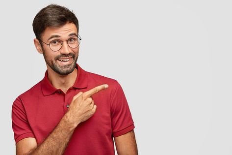 Indoor shot of positive bearded male in casual red t shirt, points with index finger aside, shows free space for your advertising content or promotional text, isolated over white background. Girls Holding Hands, Red Hair Looks, Formal Attire For Men, Surprise Face, Red Studio, Bike Drawing, Dark Blue Shirt, Photoshop Design Ideas, Facebook Cover Template