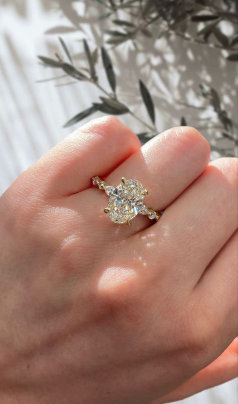 Oval Engagement Ring Accent Stones, Oval Accent Ring, Oval Engagement Ring With Side Stones Gold, Oval Shaped Engagement Rings Gold, Mosinatte Ring Gold, Ring Oval Stone, Oval Engagement Ring Curved Band, Floral Oval Engagement Ring, Gold Pave Oval Engagement Ring