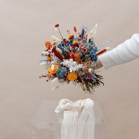 This beautiful bouquet includes a stunning combination of burnt orange and blue dried flowers, perfect for your wedding day. Our Colourful Dried Flowers Bridal Bouquet will make your special day even more special! Colourful Dried Flower Bouquet, Blue And Orange Fall Flower Arrangements, Dried Floral Bridal Bouquet, Cornflower Blue Fall Wedding, Blue Orange Bouquet, July Wedding Bouquet, Blue And Orange Bouquet, Orange And Blue Bouquet, Blue And Orange Wedding Theme