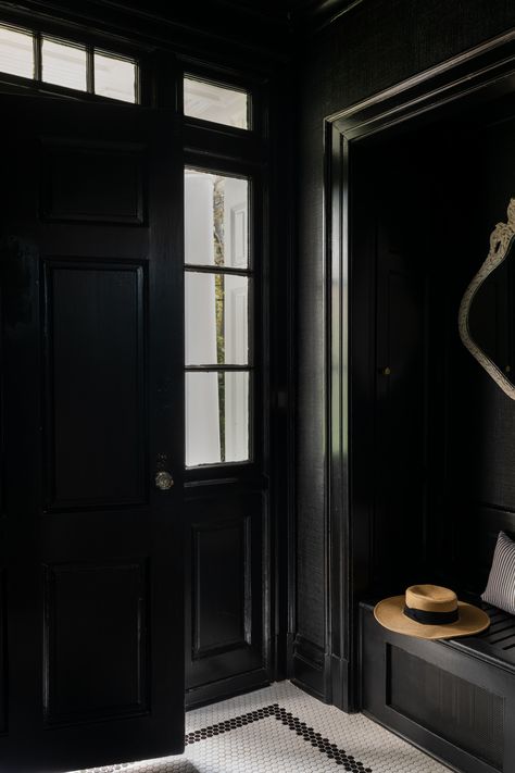 A glimpse of a beautiful entryway designed by Caroline Turner Interiors in Chicago. The space is painted completely black, including the door. Next to the door is a custom black built in to ensure that the entryway also functions as a mudroom. The floor is white vintage penny tile with a contrasting frame of black tiles. Black Vestibule, Moody Foyer, Entrance Hallways, Penny Tile Floors, Georgian Colonial, Entryway Tile, Entry Tile, Georgian Style Homes, Penny Tile