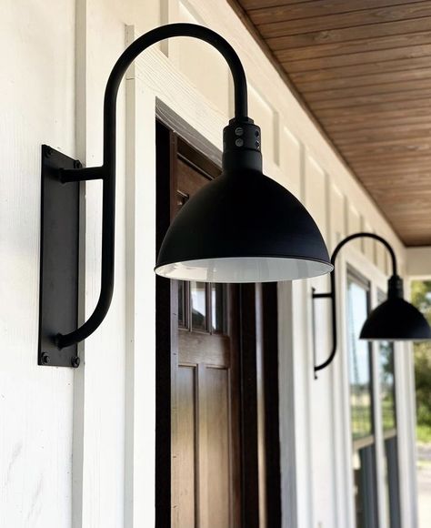 Expertly balancing its functional obligations with decorative aesthetics, the Wilcox offers multiple directional lighting alongside classic styles. For traces of uplighting, vents are cut into the neck of a classic deep bowl shade. By evoking traditional designs, this wall light feels at home in farmhouse, industrial, and contemporary décors. Farmhouse Porch Light Fixtures, Black Outdoor Farmhouse Lights, Gooseneck Porch Light, Gooseneck Lighting Outdoor Garage Doors, Barn Light Front Door, Garage Door Lights Exterior Farmhouse, Barndominium Porch Lights, Modern Farmhouse Outside Lighting, Front Porch Wall Lights