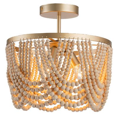 Drawing inspiration from the timeless Bohemian style, our Bohemian chandelier features oak wood beads and high-quality gold metal brackets. The layered wooden beads create captivating plays of light and shadow on the ceiling, infusing your space with a relaxed and romantic Bohemian ambiance. Finish: Gold | Bungalow Rose Pragati 3-Light Boho Wood Beaded Semi Flush Mount Wood / Metal in Yellow | 12.6 H x 12.6 W x 12.6 D in | Wayfair Dimmable Light Switch, Beaded Light Fixture, Wood Beaded Chandelier, Bohemian Chandelier, Boho Lighting, Boho Chandelier, Wood Bead Chandelier, Bedroom Light Fixtures, Empire Chandelier