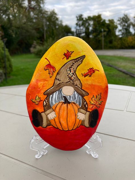 Fall Gnome Painted Rock These fall gnomes are perfect for decorating your home & garden! They make the perfect gift and add the perfect amount of fall! Each rock is hand picked from various lakes and rivers in PA. They are sealed in a gloss varnish to help protect the from weather conditions.  *No 2 rocks will be exact shape and size* Mm Painted Rocks, Scarecrow Painted Rocks Ideas, Thanksgiving Stone Painting, Painted Rocks For Fall, Rock Painting Gnomes, Thanksgiving Rocks Painted Ideas, Mushroom Painted Rocks, Fall Painted Rocks Ideas, Fall Gnomes Painting