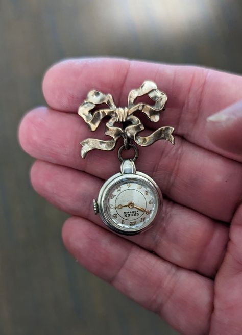 WOW! This is a special one. The gorgeous vintage Gruen watch marked 10k Gold Filled on the back, dangles from a stunning sterling silver bow that has a pin bar on the back to hang this lovely watch. It is currently NON-Working but perhaps a jeweler could get her working again. Even in  non-working conditions this piece is just lovely.  The watch measures about .75" across and from the top of the bow to the bottom of the watch is 1.75". The pearly ivory face has gold hands and numerals which I ju Vintage Watch Necklace, Watch Earrings, Victorian Steampunk Wedding, Layered Choker Necklace, Steampunk Wedding, Edwardian Jewelry, Victorian Steampunk, Steampunk Style, Antique Brooches