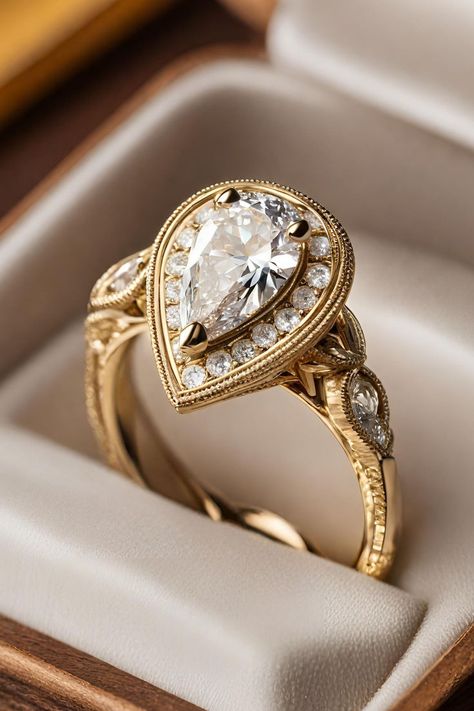 Delve into the charm of yesteryear with the Unique Vintage Halo Pear Diamond Engagement Ring, set in warm yellow gold and adorned with intricate milgrain detailing. This exquisite ring combines a pear-shaped diamond with a halo of smaller diamonds, exuding an air of sophistication and vintage elegance. Click to learn more about this stunning piece, prominently featured as number two in our list of 27 best pear engagement rings, and see how it captures the essence of antique glamour. Pear Shaped Vintage Rings, Vintage Gold Engagement Rings Antiques, Pear Engagement Ring Gold, Unique Pear Engagement Ring, Vintage Pear Engagement Ring, Gold Pear Engagement Ring, Pear Engagement Rings, Vintage Halo Engagement Ring, Gold Antique Engagement Rings