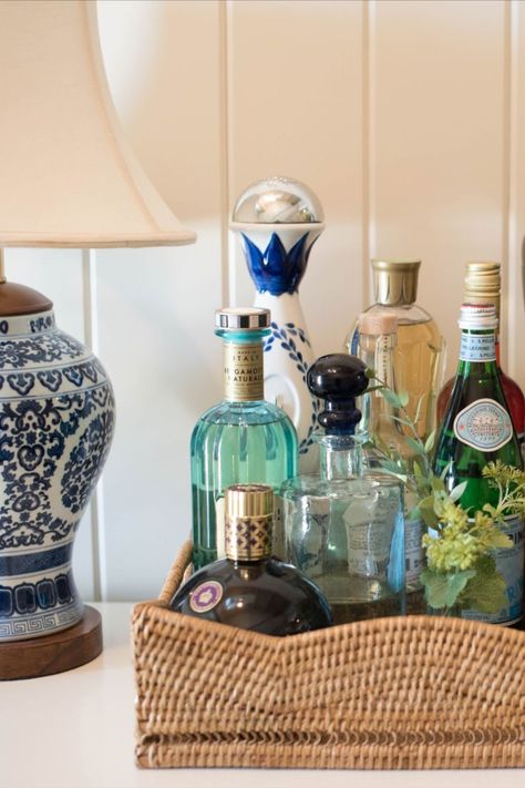 bar setup in rattan tray with blue & white ceramic lamp nearby. Home Bar Setup, Coastal Cottage Decorating, Home Bar Cabinet, Bar Setup, Southern Traditional, Home Bar Design, Bar Cart Styling, Spring Refresh, Bar Cart Decor