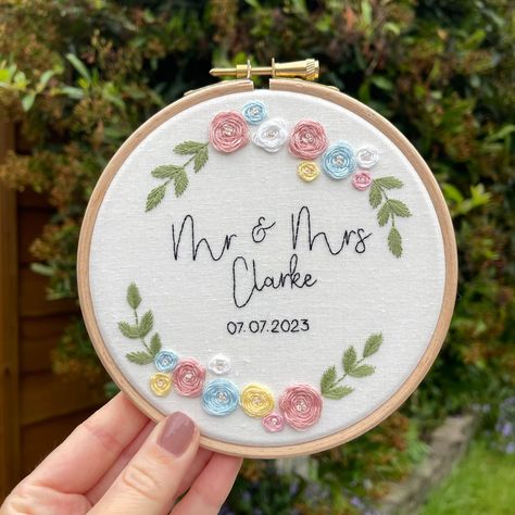 Personalised Wedding Gift & Decor Personalised Embroidery hoop perfect for the newly wedded couple. A great gift that you can hang or prop on a shelf, similar to framed photographs. Choose any names and colour of your choice! My pieces are embroidered and stitched by hand, and are completely bespoke and unique. This will be in a 5" wooden embroidery hoop and gift wrapped and packaged carefully, ready to go straight to you or to recipient of a gift. Features Personalised with name and date Personalised with any colour combinations for flowers Remember your wedding date forever, with a keepsake that will be treasured and loved Unique design and hand embroidered Luxury ivory cotton High quality embroidery thread 5" wooden, sustainably sourced embroidery hoop How To Order Enter above your pers Embroidery Hoop Border Designs, Simple Design Embroidery, Embroidery Designs With Name, Embroider Gift Ideas, Embroidery Designs Names, Embroidery Designs Gift Ideas, Wedding Embroidery Hoop Couple, Hand Embroidery Designs Simple, Name Embroidery Ideas