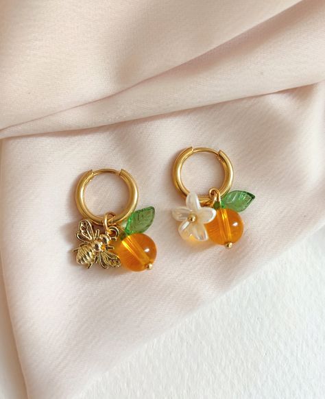 🌸 Description Earrings 🌷Judy🌷 Pretty orange fruit earrings -golden stainless steel hoop earrings -fruit style pendant, glass bead/leaf and acrylic flower/small bee in gold metal 🌸 Colors I try to obtain the most faithful color possible but depending on the phone the colors may be different. Color variations are therefore possible even if they are slight. 🌸Maintenance Tips stainless steel jewelry is resistant to water and wear but as a simple precaution to keep its beauty intact: *Avoid cont Indie Earrings, Bee Flower, Pretty Orange, Earrings Golden, Fruit Jewelry, Acrylic Flower, Fruit Earrings, Bee On Flower, Jewelry Accessories Ideas