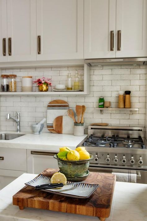 Small kitchen designed with a small range and a steel shelf above the stove mounted on white brick tiles under cream cabinets finished with vintage brass hardware. Shelf Above Stove, Accutane Before And After, White Beveled Subway Tile, White Brick Tiles, Kitchen Trends 2020, Stove Hood, Top Kitchen Trends, Cream Cabinets, Small Stove