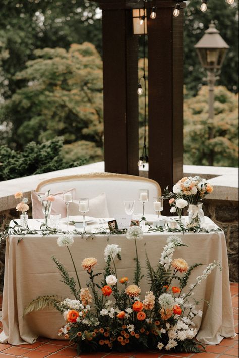 The sweetheart table with Italian ruscus runner, bud vases and a ground arrangement in front. This peach and orange palette was perfect for a summer garden wedding. Sweetheart Floral Arrangement, Spring Sweetheart Table Wedding, Front Table Decor Wedding, Sweetheart Table Ground Flowers, Wild Flower Sweetheart Table, Wedding Decor Sweetheart Table, Summer Wedding Sweetheart Table, Sweetheart Table With Bud Vases, Sweetheart Table Wedding Wildflower