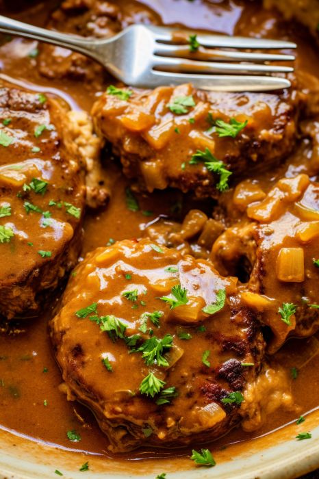 Here's a revamped version: Indulge in the savory delight of Smothered Hamburger Steak with this tantalizing recipe. Each patty boasts succulence and flavor, crafted from ground beef, onions, and peppers, generously cloaked in a luscious Hamburger Steak With Onion Gravy Recipes, Smothered Hamburger Patties Gravy, Recipes With Ground Sirloin, Smothered Patties Ground Beef, Smothered Beef Patties, Fast Hamburger Meat Recipes, Chopped Meat Recipes Ground Beef, Spanish Hamburger Recipe, Ground Beef Patties Recipes