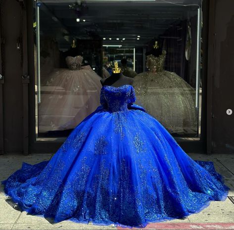 Details: Silhouette: Ball-Gown Style Fabric: Tulle Fabric Color: Royal Blue Color Length: Chapel-Train Neckline: Off-the-Shoulder Neckline Sleeves: Sleeveless Back: Lace-Up Back Embellishment: Appliqued, Bow-Knot Quince Dress Royal Blue, Quinceanera Dresses With Train, Chambelan Outfits, Blue Quince Dress, Royal Entrance, Royal Blue Ball Gown, Quince Planning, Royal Blue Quinceanera Dresses, Burgundy Quinceanera Dresses