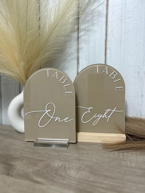 "These arched table numbers are the perfect touch to add to your wedding or party! Our table numbers come with wood or clear acrylic stands **THIS LISTING IS FOR 1 SIGN, CHANGE THE QUANTITY IN YOUR ORDER TO THE NUMBER OF TABLE SIGNS NEEDED**  For custom order with different paint colors/fonts colors than listed above, just send me a message! DIMENTIONS -Table numbers Size: 5\" x 7\" Thickness: 1/8\" - Stand Size (included with purchase)   Wood:        - 5\" Long       - 4\" Long       - 3\" Long   Acrylic Size:       - 3\" Long  HOW TO ORDER Enter the following information before adding to cart: 1) Select the paint color from the drop downs 2) choice of fully painted back or paint strokes 3) vinyl color 4) Choice of stand  5) Select the quantity of table signs needed and add to cart PRODUC Table Signs Wedding Numbers, Acrylic Number Sign, Arched Acrylic Table Numbers, Table Numbers Wedding Arch, Arched Table Numbers Wedding, Wedding Diy Table Numbers, Acrylic Arch Table Number, Table Number Signs Wedding, Arch Table Numbers Wedding