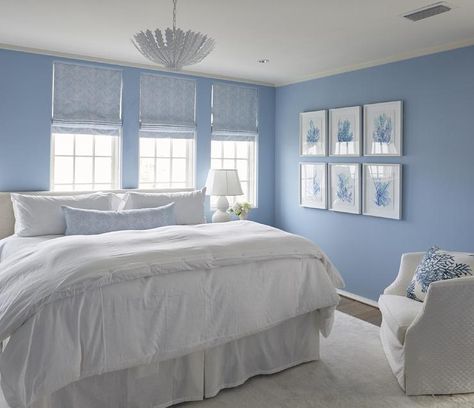 White and blue cottage bedroom boasts walls painted cornflower blue fitted with windows dressed in blue chevron roman shades placed over a white slipcovered headboard on king bed dressed in soft white bedding and a blue chevron lumbar pillow illuminated by a white pendant, Aerin Hampton Pendant, placed next to a wall lined with a blue coral art gallery. Melanie Turner, Coastal Style Bedroom, Light Blue Bedroom, Blue Room Decor, Blue Bedroom Walls, Blue Bedroom Decor, Coastal Living Rooms, Coastal Bedrooms, Cottage Bedroom