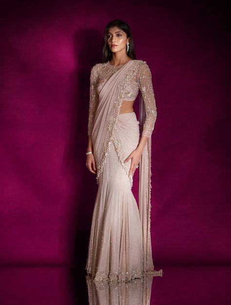 Dusty pink georgette fish style sari heavily hand embellished with pearls, silver glass beads, mixed materials & tassels, paired with a champagne and silver floral embellished sheer blouse featuring an open back.From Shloka Khialani's Winter Sun collection.DELIVERY TIMEPlease allow 6-8 weeks for your outfit to arrive.FABRIC DETAILSGeorgette, NetProfessional cleaning only. Mermaid Lehenga Indian Fashion, Western Saree Party Wear, Mummy Cocktail, Western Sarees Fashion, Outfit For Sangeet Function, Saree With Shrug, Western Sarees, Mermaid Saree, Bridal Reception Saree