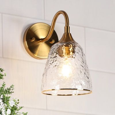 Update your sophisticated bathroom, living room, or bedroom with this glam 1-light wall sconce. This wall sconce brings a sleek silhouette and ambient light to any room. It's made from iron with a copper-gold finish, and it has a water-grained glass bell shade for an elevated look. This sconce includes a circular backplate and a curved arm that supports the shade. It accommodates one E26, Type A, Max 60W bulb (not included), and it's dimmer-switch compatible to set the mood. With its minimalist Brushed Bronze Bathroom Fixtures, Bath Tub Lighting, Boho Family Room, Powder Room Lighting, Gold Sconces, Bathroom Wall Lighting, Loft Penthouse, Sconces Bathroom, Sophisticated Bathroom