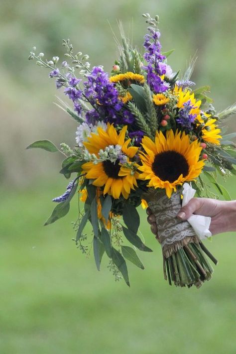 a bold wedding bouquet made of sunflowers, purple and white blooms and much greenery and wheat Sunflowers And Lilacs, Sage Green Bridesmaid Dresses With Sunflower Bouquet, Sunflower And Lilac Bouquet, Western Wedding Sunflowers, Purple Black Sunflower Wedding, Wedding Dress Sunflower, Sunflowers Bouquet Wedding, Sunflower Pampas Bouquet, Wheat And Eucalyptus Bouquet