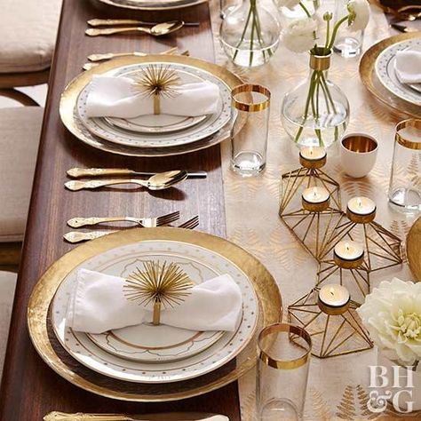 For a contemporary look, stick with plain white and gold accents. Just roll a white cloth napkin and secure with a fun gold napkin ring. Continue the gold accents throughout the table decor. White And Gold Dining Table Decor, Dining Table Napkins Decor, Fancy Table Decor, White And Gold Table Setting, Fine Dining Table Setting, White Dinner Table, Gold Table Decor, Gold Table Setting, White Table Settings