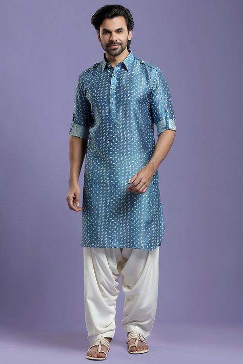 Featuring an indigo blue kurta in blended silk base with a shirt collar, roll-up sleeves, and bandhani print. It is paired with contrasting off-white salwar pants.  FIT: True to size. COMPOSITION: Blended silk. CARE: Dry clean only. Bandhani Kurta For Men, Pleated Salwar, White Salwar, Navratri Outfits, Wedding Kurta, Wedding Kurta For Men, Bandhani Print, Salwar Pants, Shirt Outfit Men