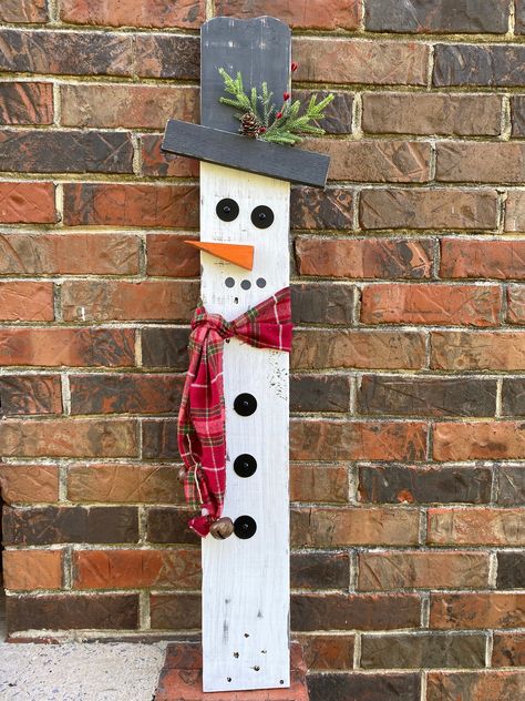 "These wooden snowmen yard or porch decorations are made using reclaimed pallet wood, painted white with a white wash effect. Scarf is fabric and will rival over time to add to the rustic effect.  The snowman has a red checkered scarf, with rustic jingle bells on the ends.  These snowmen can be propped up or be purchased with hardware to set in your yard. That would include the metal brackets as well as the metal post. These are sold separately but can be purchased as a set. Measurements: 34.5\"x5\" snowman 34\"x5.5\" snowwomen These are individuals and can be placed close to each other or apart. Due to the nature of using reclaimed wood, we can not guarantee each snowman will look the same as the picture. We will do our best to ensure that they match.  More in our shop: Decorative tray: h Christmas Decor Pallet Wood, Diy Christmas Decorations For Outside Wood, Wooden Snowman Diy, Diy Wooden Porch Signs, Reversible Scarecrow Snowman, Pallet Board Crafts, Wooden Snowman Crafts Wood Patterns, Pallet Wood Christmas Decor, Front Porch Diy Ideas