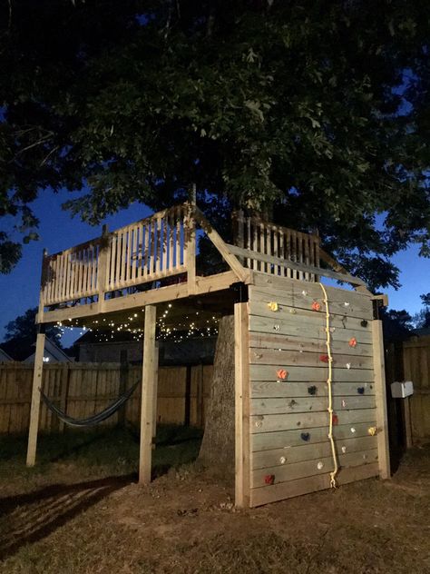 Treehouse Platform with Rocking Climbing Wall. Hammock. String Lights. No damage to the tree Tree House Climbing Wall, Treehouse Platform Ideas, Treehouse No Tree, Treehouse Climbing Wall, No Tree Treehouse, Backyard Rock Climbing Wall, Platform Treehouse For Kids, Platform Treehouse, Platform Tree House