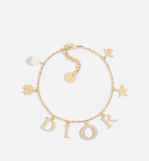 The Dio(r)evolution bracelet is a creation with a modern aesthetic. The Dior letters are suspended from a gold-finish metal chain, while the pavé of silver-tone crystals adorning the letter O adds a luminous touch. The design is embellished with a white resin pearl and signature Dior symbols, including stars, the clover and the bee. The sophisticated bracelet can be combined with other creations from the Dio(r)evolution line.. Dior Charm Bracelet, Dior Armband, Dior Bracelet Gold, Bracelet Dior, Dior Jewellery, Dior Bracelet, Resin Pearl, Preppy Jewelry, Dior Jewelry