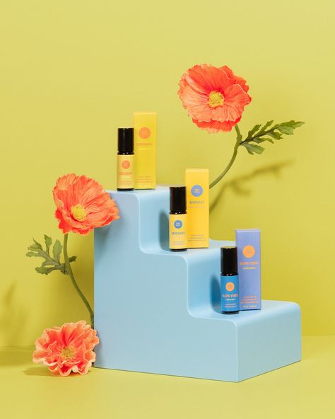 3 aromatherapy oils on a blue prop shaped like a set of stairs - with three levels. There are orange poppies around the stairs and the backdrop is a chartreuse color. The aromatherapy oils are from Thought Sanctuary. Bright Colorful Product Photography, Product Photography Trends 2023, Props Product Photography, Stylized Product Photography, Color Block Product Photography, Conceptual Product Photography, Product Photography Colorful, Colourful Product Photography, Bright Product Photography